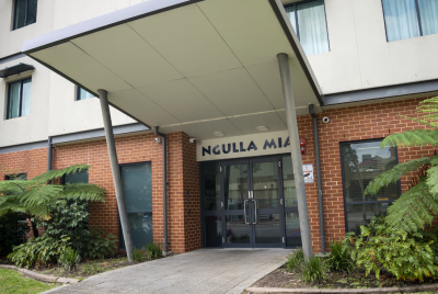 Entrance to Ngulla Mia Supported Accommodation, a building with brick on the bottom and cream coloured walls above