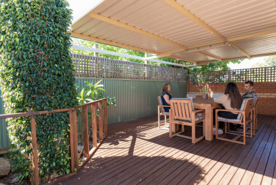 Three people sitting outside on a wooden table on a wooden deck