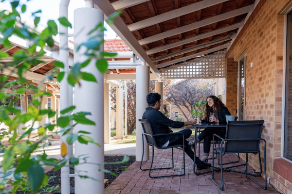two people outside drinking coffee and talking