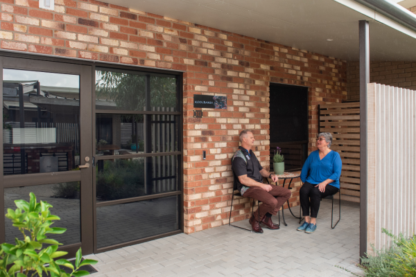 two people sitting and talking outside a building entrance