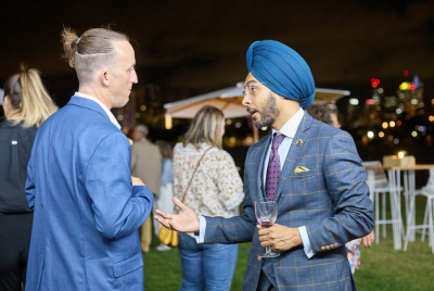 Two men in blue suits talking at an event in the grass at night