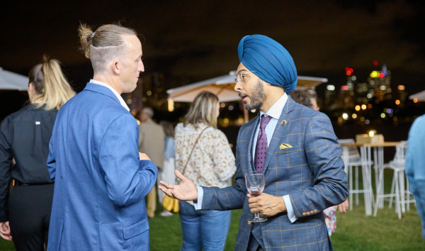 Two men in blue suits talking at an event in the grass at night
