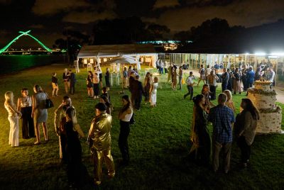 A group of people at an event at night on the grass in front of some buildings