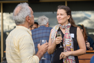 A woman in a colourful scarf holding a drink and speaking with a man who is also holding a drink