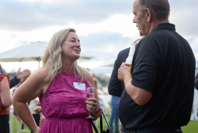 A woman in a pink dress holding a drink and talking to a man in a black shirt at an event