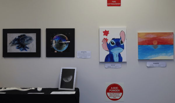 A white wall with various decorations including a picture of Stitch from the Disney movie, a picture of a sunset, an image of the moon and an image of a bubble