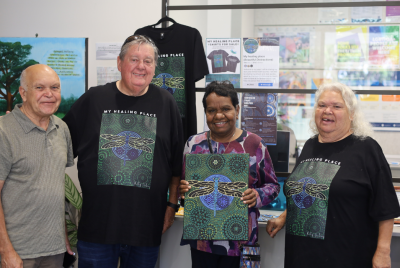 Two men and two women standing together for a photo and smiling while one of the women holds a piece of art