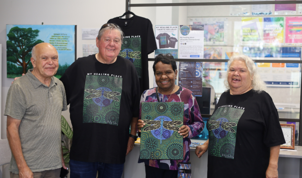Two men and two women standing together for a photo and smiling while one of the women holds a piece of art