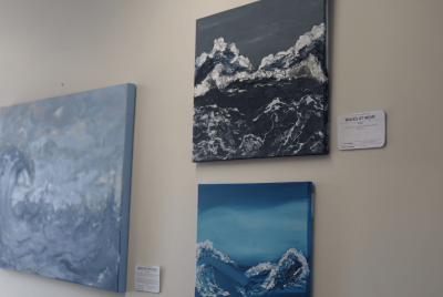 Three blue paintings of the ocean displayed on a white wall