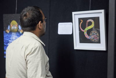 A man looking at a piece of art that displays a rainbow snake