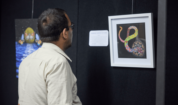 A man looking at a piece of art that displays a rainbow snake