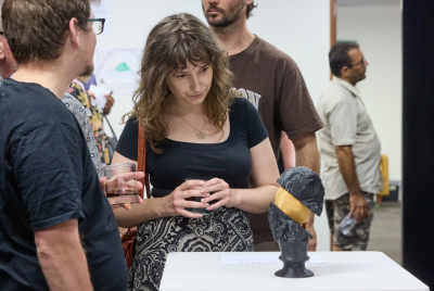 A woman standing with a man and looking at a black and gold sculpture on display at an exhibition