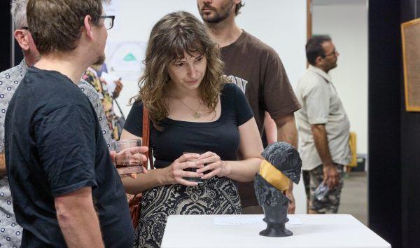 A woman standing with a man and looking at a black and gold sculpture on display at an exhibition