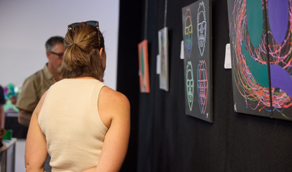 A woman and a man looking at various colourful pieces of art at an exhibition