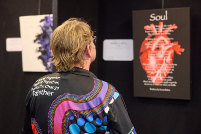 A man in a black shirt with aboriginal patterns looking at a display about the soul