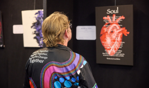 A man in a black shirt with aboriginal patterns looking at a display about the soul