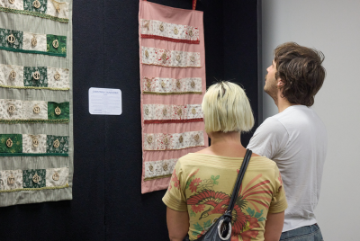 A man and a woman at an exhibition looking at a pink piece of art at an exhibition