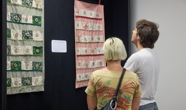 A man and a woman at an exhibition looking at a pink piece of art at an exhibition