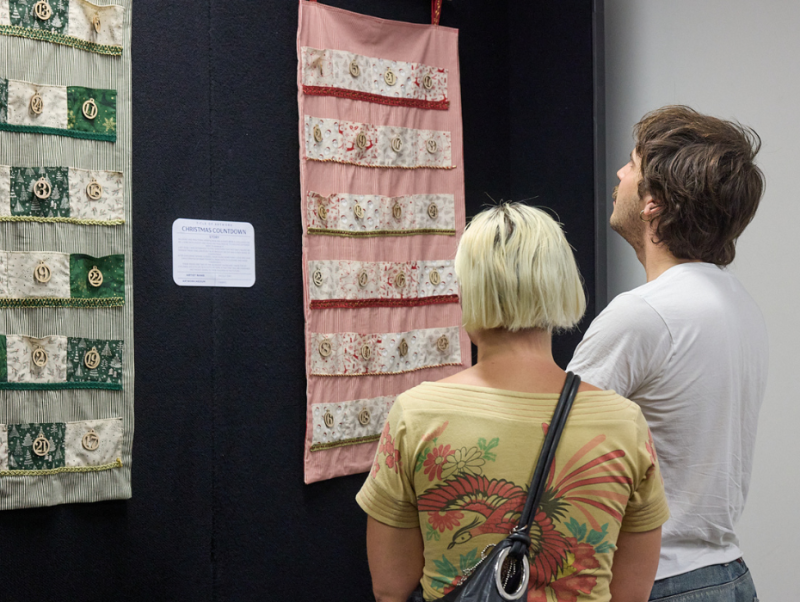 A man and a woman at an exhibition looking at a pink piece of art at an exhibition