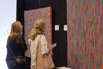 Two women at an exhibition looking at some multicoloured pieces of abstract art at an exhibition