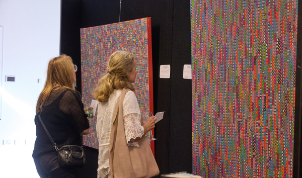 Two women at an exhibition looking at some multicoloured pieces of abstract art at an exhibition
