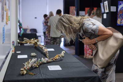 A woman bending forward to look at a long sculpture at an exhibition