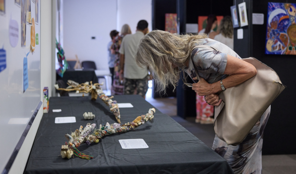A woman bending forward to look at a long sculpture at an exhibition