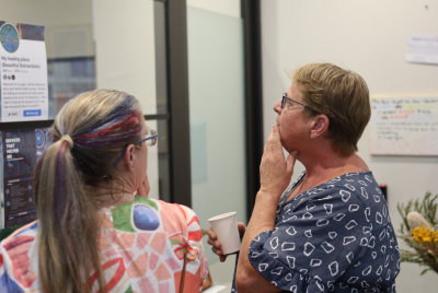 Two women standing in front of an exhibit and speaking to each other