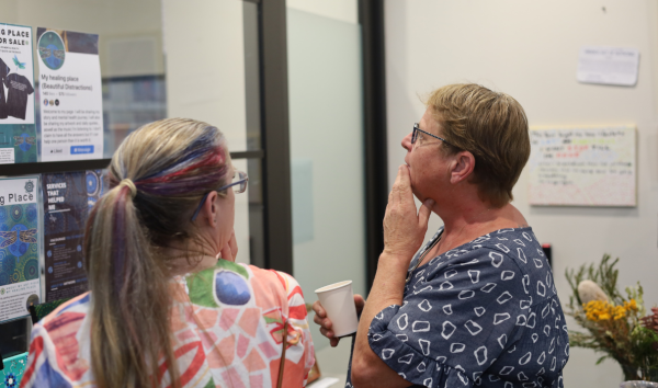 Two women standing in front of an exhibit and speaking to each other