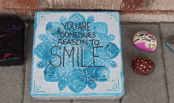 A blue and white stone cube with the you are someone's reason to smile written on it in black icing