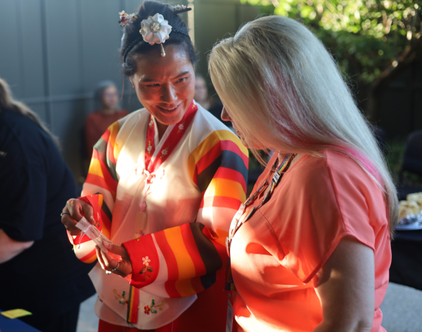 A woman in scrubs speaking to a woman in a traditional outfit