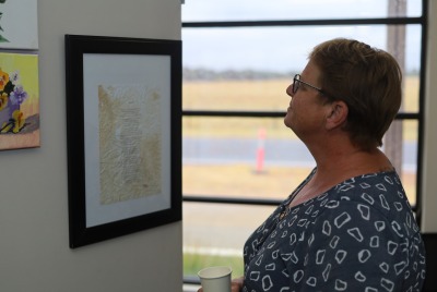 A woman looking at a framed document hanging on a wall
