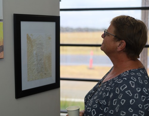 A woman looking at a framed document hanging on a wall