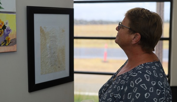 A woman looking at a framed document hanging on a wall
