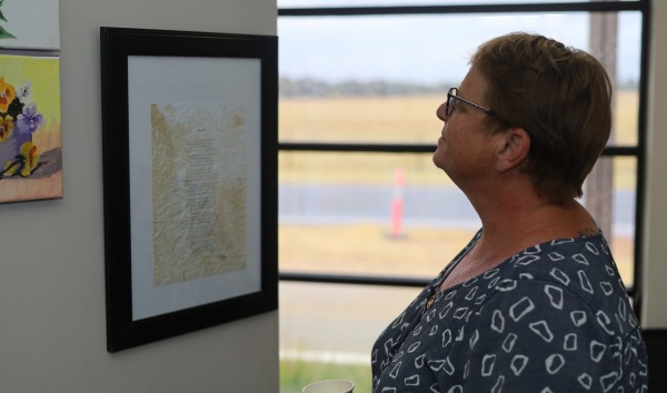 A woman looking at a framed document hanging on a wall
