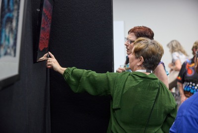 Two women pointing at a piece of art and discussing it at the Heart and Soul exhibition