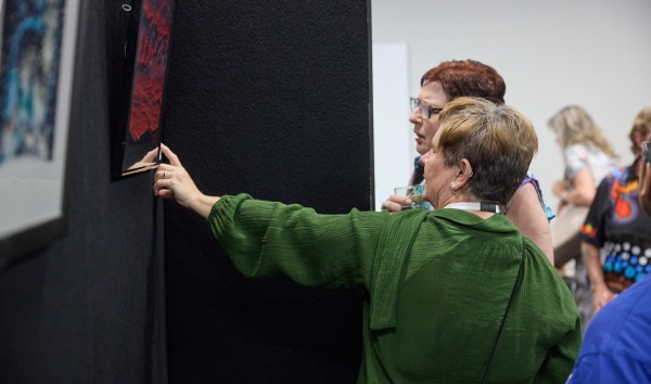 Two women pointing at a piece of art and discussing it at the Heart and Soul exhibition