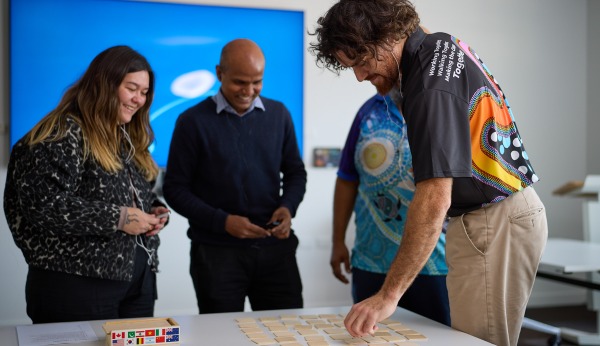 People standing around a table with one man pointing towards small cards