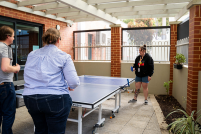 Three people around a table tennis table holding paddles
