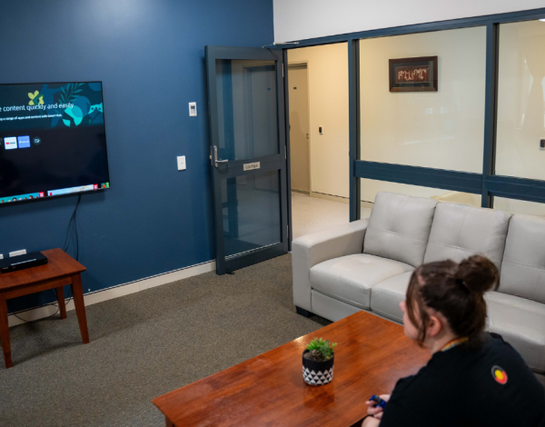 A woman sitting on a couch in a room and watching television