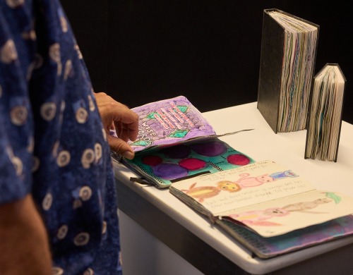Someone looking at some artwork on a table at the Heart and Soul exhibition