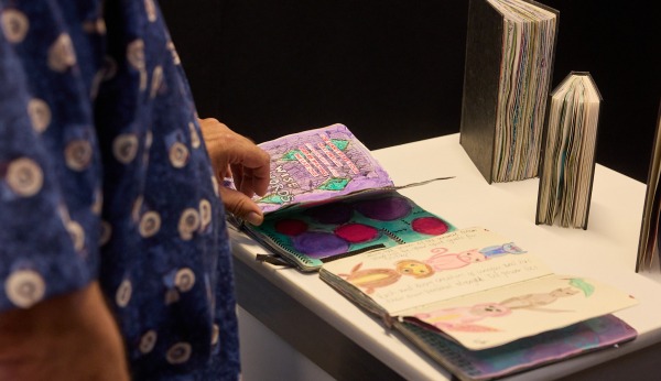 Someone looking at some artwork on a table at the Heart and Soul exhibition