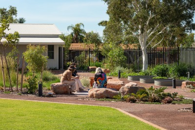 The outdoor area of the Karratha Step Up/Step Down service building with a few women sitting on some rocks