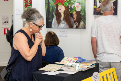 A woman looking at a few art books at the Heart and Soul exhibition