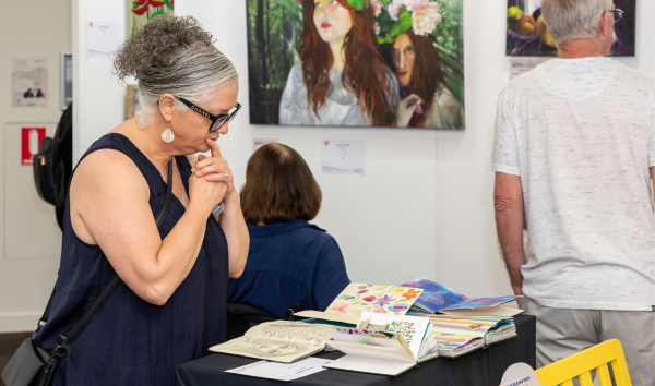 A woman looking at a few art books at the Heart and Soul exhibition