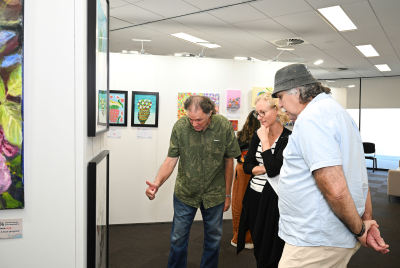 Two men and a woman looking at one of the paintings at the Heart and Soul Exhibition