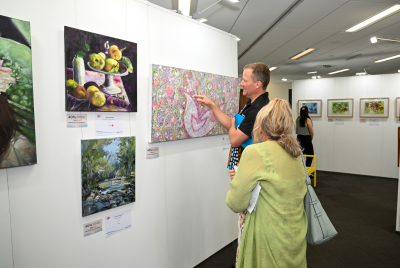 A man and a woman looking at some of the different paintings at the Heart and Soul Exhibition