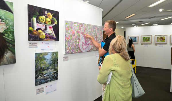 A man and a woman looking at some of the different paintings at the Heart and Soul Exhibition