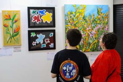 A boy and a woman looking at some of the paintings from the Heart and Soul exhibition