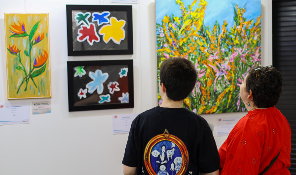 A boy and a woman looking at some of the paintings from the Heart and Soul exhibition